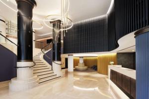 a lobby with a staircase and a chandelier at Rydges Darling Square Apartment Hotel in Sydney
