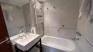 a white bathroom with a sink and a tub at Apartamentos del Centro - BARILOCHE in San Carlos de Bariloche