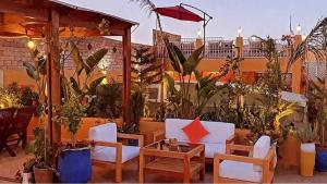 a patio with white chairs and an umbrella and plants at Riad Moulaydriss et Giacomo in Fez