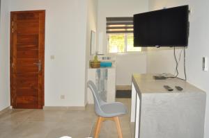 Habitación con silla y escritorio con TV. en Keur de Pierre, en Saly Portudal