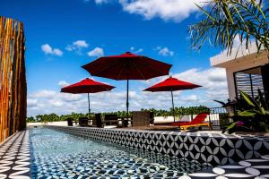 einen Pool mit roten Sonnenschirmen und Stühlen neben einem Pool in der Unterkunft Dreamcatcher Tulum in Tulum
