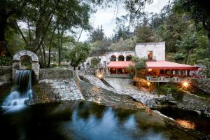 un bâtiment avec une cascade à côté d'une rivière dans l'établissement Molino de los Reyes By Rotamundos, à Totolac