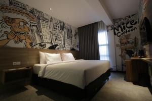 a bedroom with a large bed with a mural on the wall at Creative Restart Hotel - CARTEL Bandung in Bandung