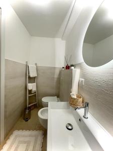 La salle de bains blanche est pourvue d'un lavabo et de toilettes. dans l'établissement Casa di zia Pupetta, à Bari