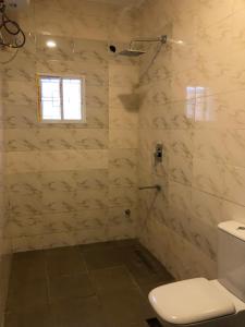 a white bathroom with a toilet and a window at Well furnished and very spacious apartment in Wuye in Abuja