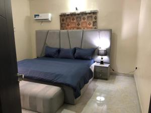 a bedroom with a bed with a headboard and a lamp at Well furnished and very spacious apartment in Wuye in Abuja