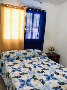 a bed with a blue and white quilt in a bedroom at Apto 2Habitaciones con Aire y Vista al Malecón de Samaná in Santa Bárbara de Samaná
