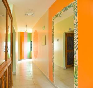 einen Flur mit orangefarbener Wand und Spiegel in der Unterkunft Distrito Hostel in Santa Marta