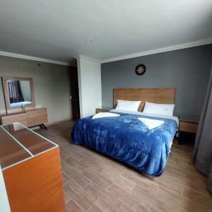 a bedroom with a large bed with a blue blanket at Hotel Santino in Toluca