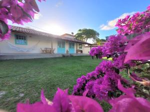 une maison avec des fleurs violettes dans la cour dans l'établissement Vila dos Lençóis, à Santa Cruz Cabrália