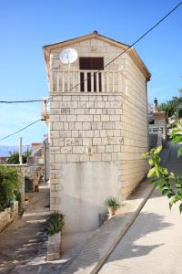 a brick building with a clock on top of it at Apartments by the sea Povlja, Brac - 5644 in Povlja