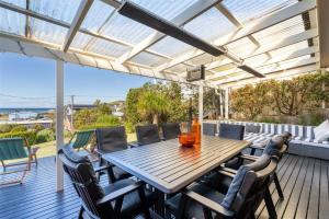 a patio with a wooden table and chairs on a deck at Casa Moana in Gerringong