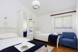 1 dormitorio con 2 camas y silla azul en Apartments by the sea Podgora, Makarska - 11432, en Podgora