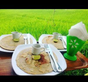 stół z dwoma talerzami jedzenia i dwoma kubkami i naczyniami w obiekcie GumiBali Villa w mieście Tirtagangga