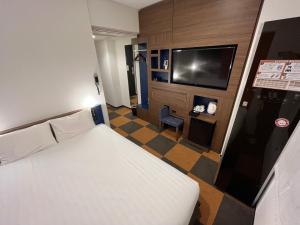 a hotel room with a bed and a flat screen tv at Henn na Hotel Tokyo Haneda in Tokyo