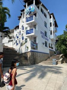 a woman wearing a mask walks in front of a building at Hotel & Hostal Mayflower in Puerto Escondido