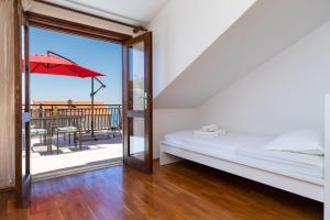 - une chambre avec un lit et un balcon avec un parasol dans l'établissement Apartments by the sea Sumpetar, Omis - 11462, à Jesenice