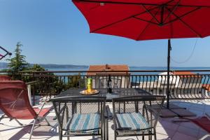 - une table avec des chaises et un parasol sur le balcon dans l'établissement Apartments by the sea Sumpetar, Omis - 11462, à Jesenice