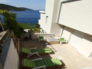 a patio with two green chairs and a table at Apartments by the sea Savar, Dugi otok - 11540 in Brbinj