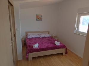 a bedroom with a bed with purple sheets and a window at Apartments by the sea Savar, Dugi otok - 11540 in Brbinj