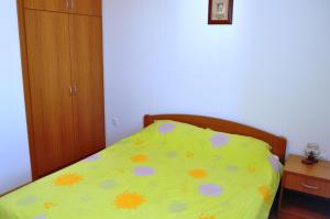 a bed with a yellow comforter with flowers on it at Apartments with a parking space Selce, Crikvenica - 11527 in Selce
