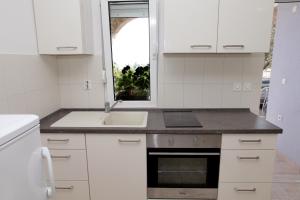 eine Küche mit weißen Schränken und einer Spüle und einem Fenster in der Unterkunft Apartments with a parking space Mavarstica, Ciovo - 11563 in Trogir
