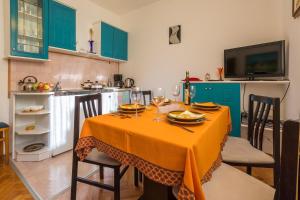 uma cozinha com uma mesa com uma toalha de mesa laranja em Apartments with a parking space Klenovica, Novi Vinodolski - 11559 em Klenovica