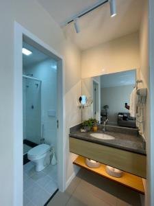 a bathroom with a sink and a toilet and a mirror at Flat PRAIA de Camburi in Vitória