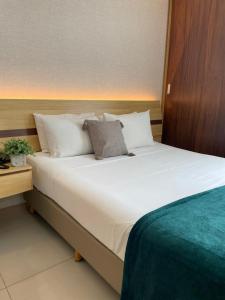 uma grande cama branca num quarto de hotel em Flat PRAIA de Camburi em Vitória
