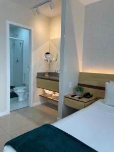 a bedroom with a bed and a bathroom with a sink at Flat PRAIA de Camburi in Vitória
