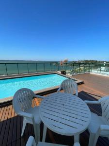 a table and chairs on a deck with a swimming pool at Flat PRAIA de Camburi in Vitória