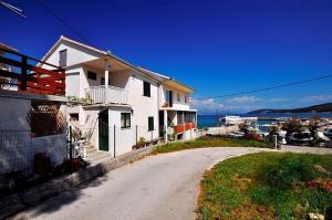 ein weißes Haus auf einer Straße neben dem Wasser in der Unterkunft Apartments by the sea Slatine, Ciovo - 11565 in Slatine