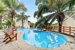 a swimming pool with two chairs and palm trees at Colorful, Classy, Modern Split-Level Near Beach with Pool in Coco