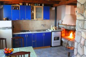 a kitchen with blue cabinets and a stone fireplace at Seaside family friendly house with a swimming pool Cove Pernatice, Drvenik - 11590 in Drvenik Veli
