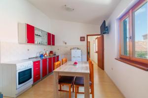 una cocina con armarios rojos y una mesa con sillas. en Apartments by the sea Kukljica, Ugljan - 11584, en Kukljica