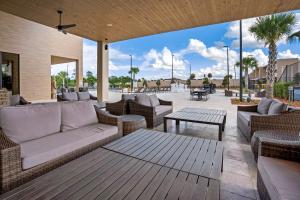 een overdekte patio met banken, tafels en palmbomen bij Beautiful townhome Magic Village 1,5 mile to Dis in Orlando