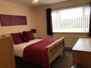 a bedroom with a bed with red sheets and a window at The Bungalow, Lingdale in Lingdale