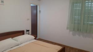 a small bedroom with a bed and a window at Apartment Sveta Nedilja 11433a in Jelsa