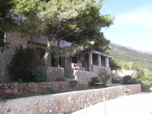 a stone house with a stone wall and a tree at Apartments by the sea Sveta Nedilja, Hvar - 11433 in Sveta Nedelja