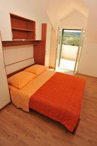 a bedroom with a bed with an orange blanket at Holiday house with a swimming pool Sutivan, Brac - 11496 in Sutivan