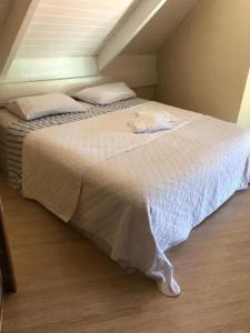 1 dormitorio con 1 cama grande con sábanas y almohadas blancas en Pousada Reserva do Tombo Lounge Hostel en Guarujá