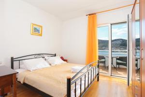 um quarto com uma cama e uma varanda com uma mesa em Apartments by the sea Seget Vranjica, Trogir - 13771 em Trogir