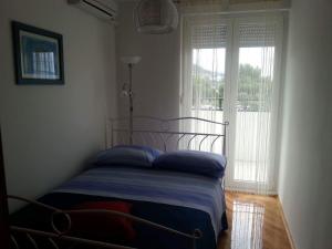 a bedroom with a bed with blue pillows and a window at Apartments by the sea Omis - 13796 in Omiš