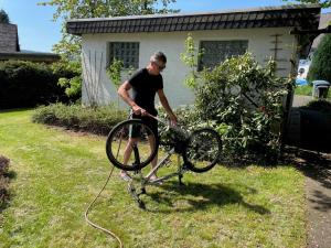 Ein Mann wäscht ein Fahrrad im Hof in der Unterkunft Auf der Platte 1 in Winterberg