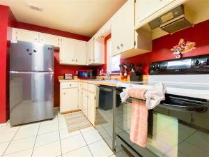a kitchen with red walls and a stainless steel refrigerator at 2 Bed 5325 in Kissimmee