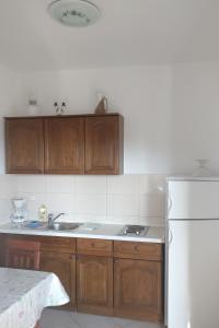 - une cuisine avec des placards en bois et un réfrigérateur blanc dans l'établissement Apartments with a parking space Grebastica, Sibenik - 13860, à Bašelovići