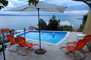 basen z 2 krzesłami i parasolem w obiekcie Seaside apartments with a swimming pool Krilo Jesenice, Omis - 13898 w mieście Jesenice