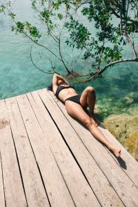 a woman laying on a dock in the water at Azul Nomeolvides Bacalar - Lagoon Front in Bacalar