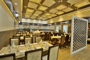 un restaurante con mesas y sillas en una habitación en Jhansi Hotel, en v