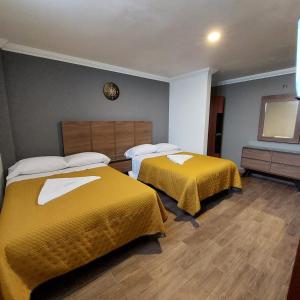 two beds in a hotel room with yellow sheets at Hotel Santino in Toluca